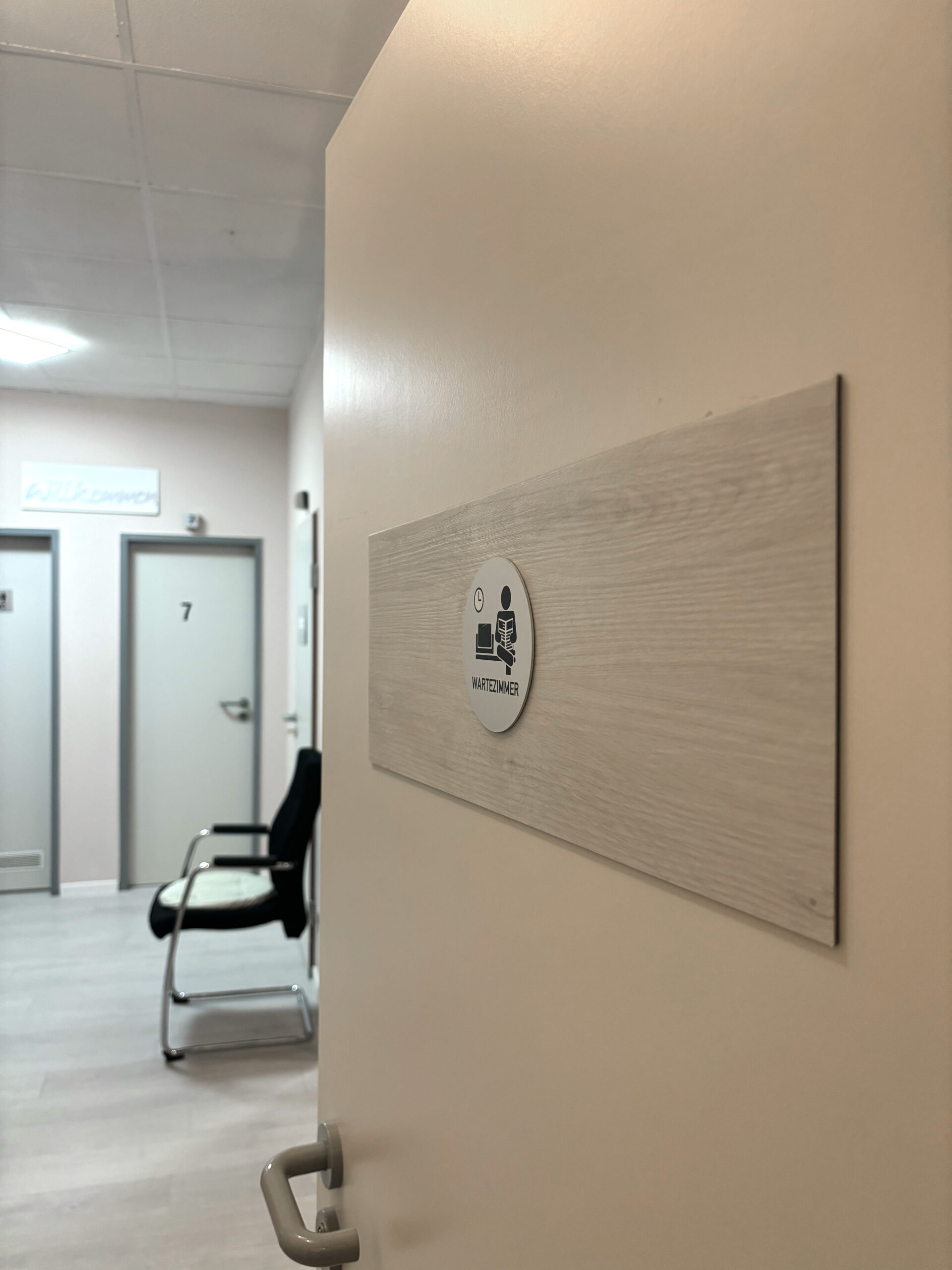 Einblick ins helle Wartezimmer von Physio Ganster, im Hintergrund sind Türen zu Behandlungsräumen zu den Therapeuten